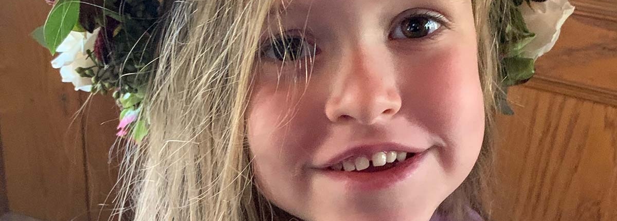 little girl smiles into camera with big flower crown on head