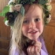little girl smiles into camera with big flower crown on head